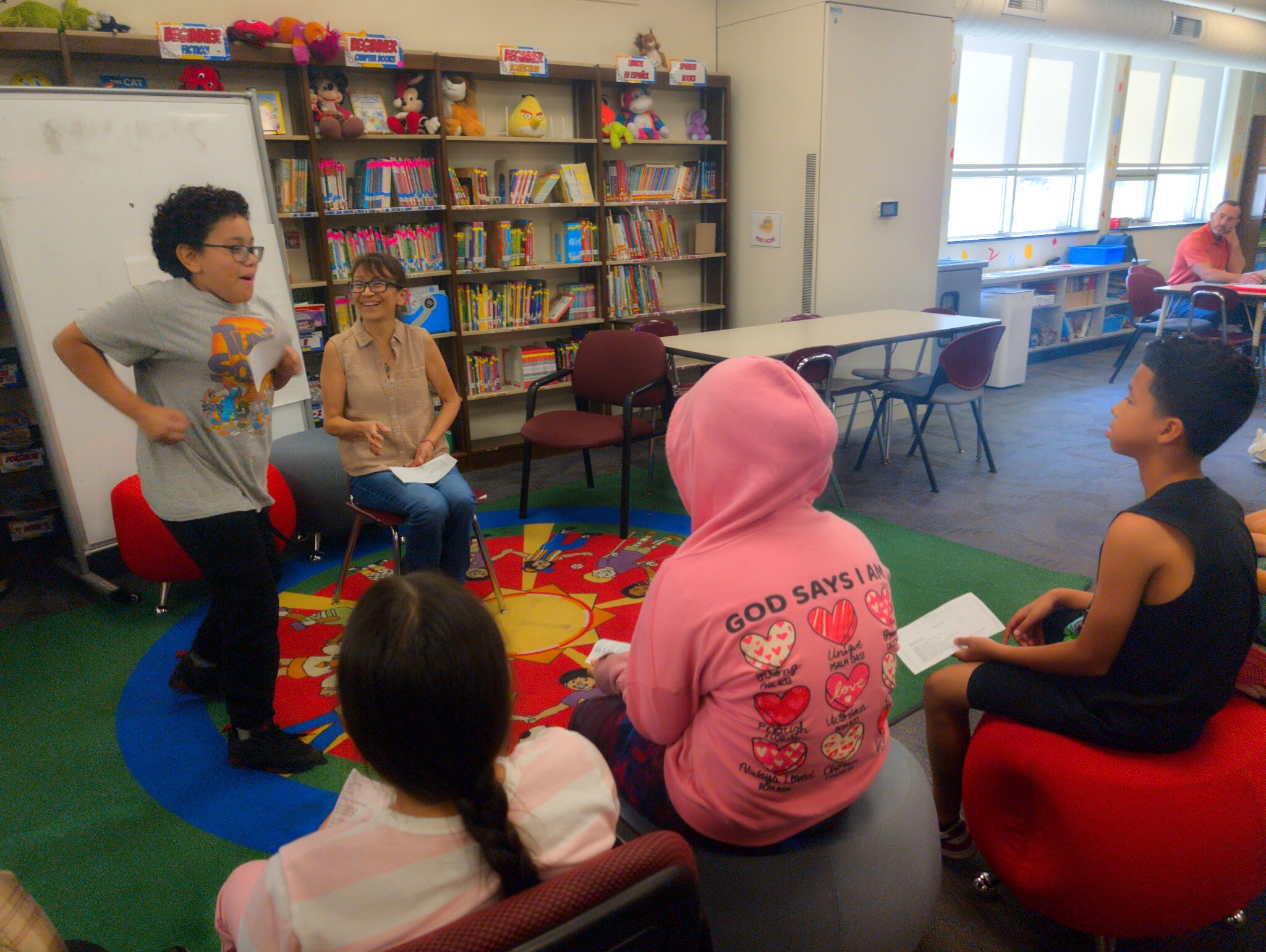 Young performer speaking to a seated group during a theatre exercise