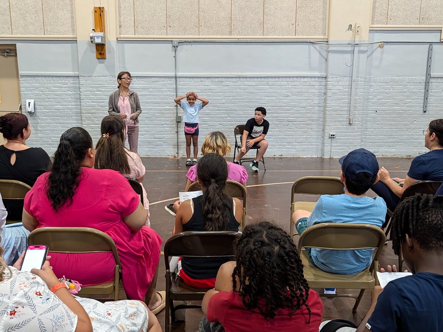 Young performers presenting a scene to an audience in a large room