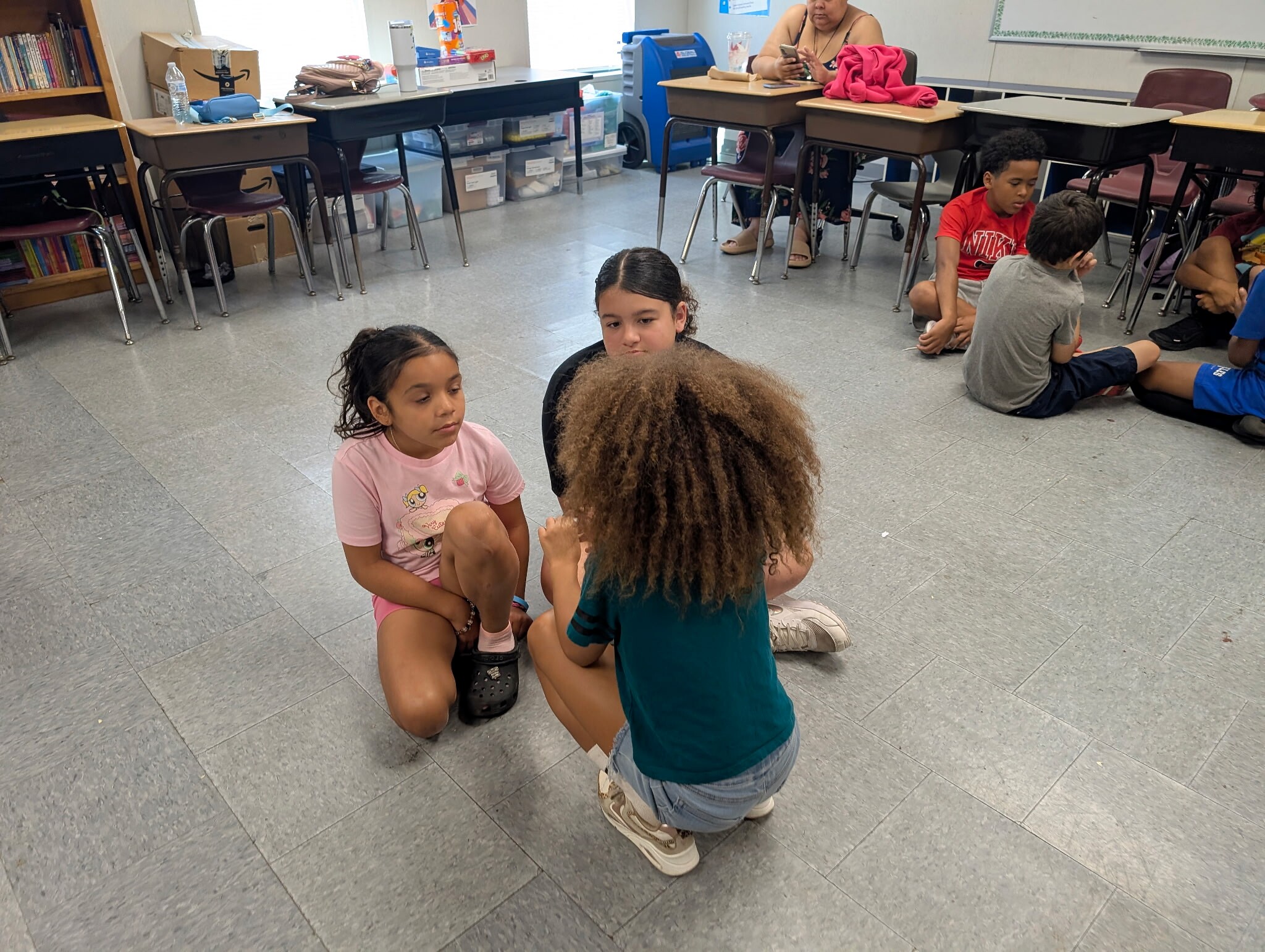 Three students seated on the floor developing a scene together